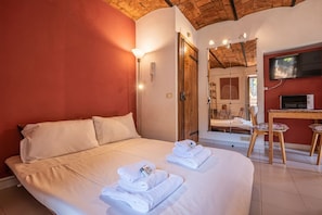 Een hotelkamer met een groot bed, een televisie, een open haard en een houten plafond.