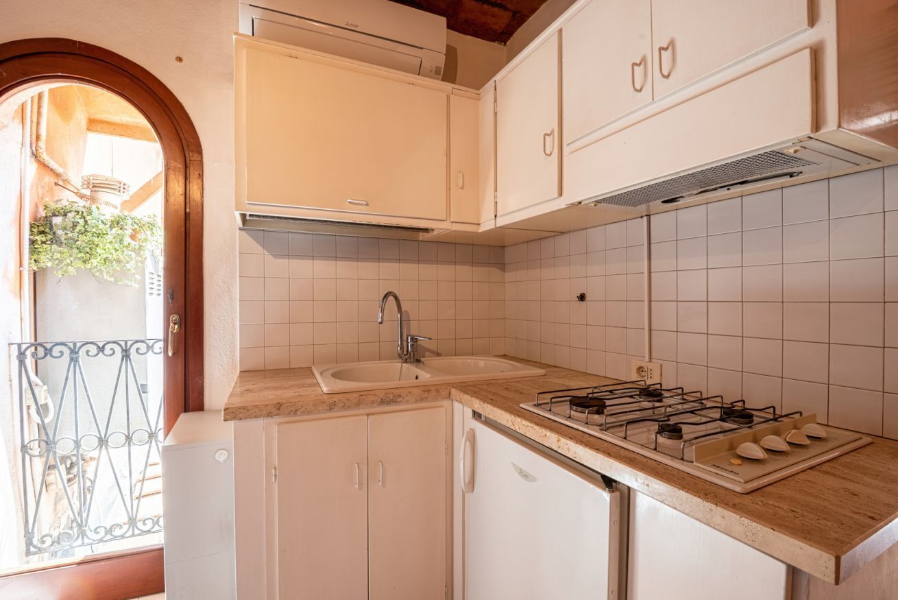 A kitchen with white cabinets, a double sink, a gas stove, and a window with a view of greenery.
