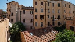Ein mehrgeschossiges Gebäude mit Balkonen, Satellitenschüsseln und unterschiedlichen Fensterformen.
