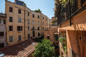 Une rue étroite bordée d’immeubles dotés de balcons et de climatiseurs, avec un arbre au premier plan.