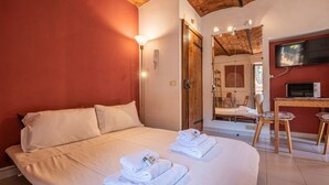 Ein Hotelzimmer mit einem großen Bett, einem Fernseher, einem Kamin und einer Holzbalkendecke.