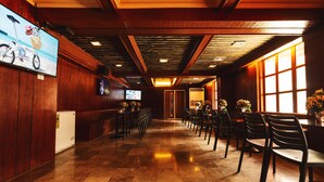 A hotel lobby with wooden paneling, a tiled floor, and a long reception desk with chairs.