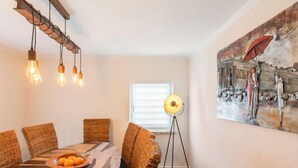 A dining area with a wooden table, wicker chairs, and a modern pendant light.