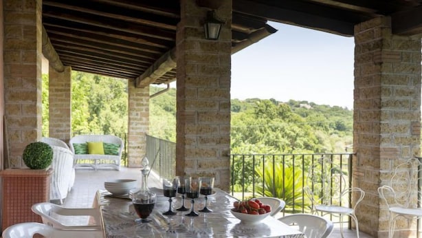 Une terrasse extérieure avec une table dressée pour le repas, entourée de piliers en pierre et offrant une vue sur une végétation luxuriante.