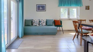 A living room with a sofa, a dining table with chairs, a window with curtains, and a framed picture on the wall. - Maslina by Interhome (Pula/Duga uvala)