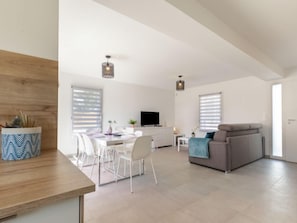Un vaste espace de vie comprenant une table à manger, des chaises, un canapé et un téléviseur.