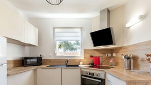 A compact kitchen with a microwave, oven, and a window. - Vacation home Vinci by Interhome (Royan)