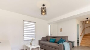 A modern living room with a grey sofa, a small white side table, and a staircase leading to another level. - Vacation home Vinci by Interhome (Royan)