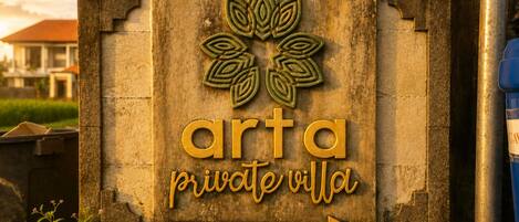 Un letrero con el texto 'arta private villa' y una flecha señalando la dirección.