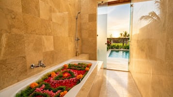 Baño con una bañera llena de flores, una ducha y vistas a una piscina exterior.
