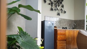 A modern kitchen with a stainless steel refrigerator, wooden cabinets, and a decorative wall art piece. - Arta Private Villa (Ubud)