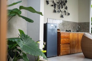 Une cuisine moderne avec un réfrigérateur en acier inoxydable, des armoires en bois et une œuvre d’art décorative accrochée au mur.
