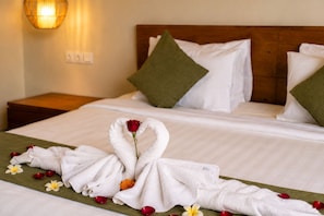 A hotel room with a neatly made bed, a wooden headboard, and a wall-mounted light fixture. - Arta Private Villa (Ubud)