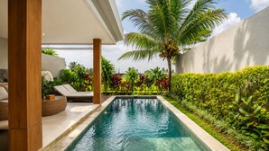 A swimming pool with a view of a palm tree and a hedge. - Arta Private Villa (Ubud)