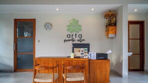 A reception desk with two wooden chairs, a clock, and a wall-mounted sign reading "arta private villa". - Arta Private Villa (Ubud)