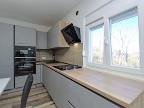 A modern kitchen with built-in appliances, a window with a view, and a wooden countertop. - Vacation home Aurora by Interhome (Skradin)