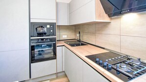 Een moderne keuken met roestvrijstalen apparatuur, een inbouwoven en een gasfornuis.
