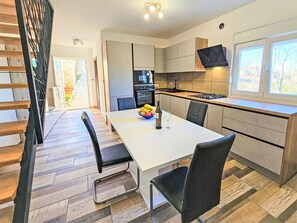Cozinha moderna com área de refeições, piso de madeira e televisão montada acima do balcão.