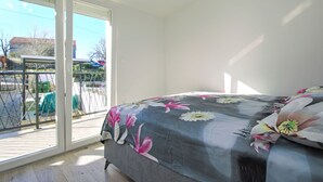 Een slaapkamer met een bed, een schuifdeur naar een buitenruimte en uitzicht op de omgeving.
