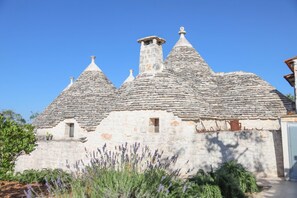 A traditional stone building with conical roofs and a central chimney.