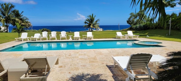 Une piscine avec des chaises longues et vue sur l’océan.