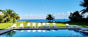 A pool with white chairs and a view of the ocean. - Casa Los Sue os in Punta Cana (Sosúa)