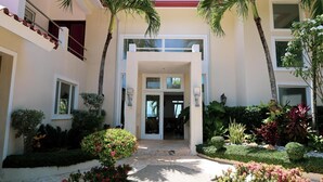 A modern building with a central entrance, surrounded by well-maintained gardens and palm trees. - Casa Los Sue os in Punta Cana (Sosúa)