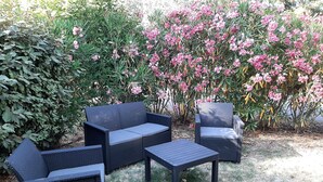 Ein Patio mit einer dunklen Rattan-Couch, zwei Sesseln und einem kleinen Tisch.
