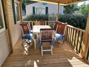 A wooden deck with a table and four chairs, surrounded by a wooden railing.