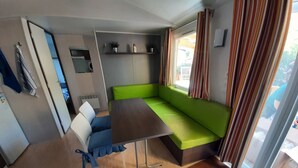 Ein gemütlicher Wohnraum mit einem grünen Sofa, einem kleinen Tisch und einem fenster mit Vorhängen.