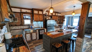 A kitchen with wooden cabinets, a central island with stools, a built-in oven, and a refrigerator. - Enjoy relaxing comfort in this uniquely designed home - 5min from Frontier Park (Cheyenne)