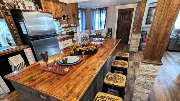 A kitchen with a wooden island, bar stools, and a refrigerator. - Enjoy relaxing comfort in this uniquely designed home - 5min from Frontier Park (Cheyenne)