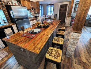 A kitchen with a wooden island, bar stools, and a refrigerator.