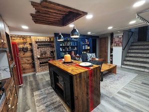 A kitchen with a central island, wooden cabinets, and a brick wall.