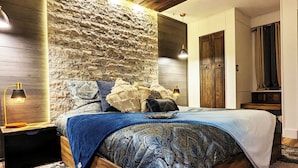 A bedroom with a wooden bed, a stone wall, and a modern ceiling design. - Enjoy relaxing comfort in this uniquely designed home - 5min from Frontier Park (Cheyenne)