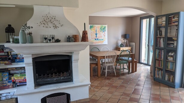 Una sala de estar con chimenea, comedor y estantería.