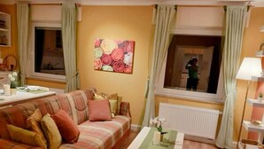 Una sala de estar acogedora con un sofá a cuadros, una mesa de centro de vidrio y un ventanal con cortinas.