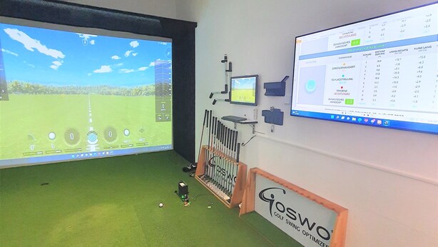 Un gimnasio de entrenamiento de golf con varias pantallas que muestran simulaciones y datos de rendimiento.