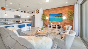 A modern living room with a grey sofa, a coffee table, and a TV wall mounted above a wooden accent wall. - Stunning Lake View! Themed Bedrooms With Comfortable and Sophisticated Decor (Kissimmee)