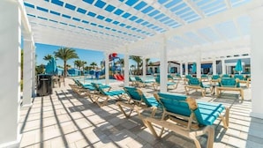 A covered pool area with sun loungers and a water slide. - Stunning Lake View! Themed Bedrooms With Comfortable and Sophisticated Decor (Kissimmee)