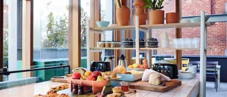 Un bufé de desayuno con diferentes opciones de comida, una estación de café y estantes con utensilios de cocina.