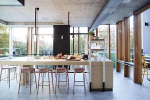 Una cocina moderna con una isla central, taburetes de bar y amplios ventanales con vistas a la ciudad.