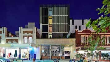A modern building with a glass facade, a parking area with motorcycles, and a storefront with a sign.