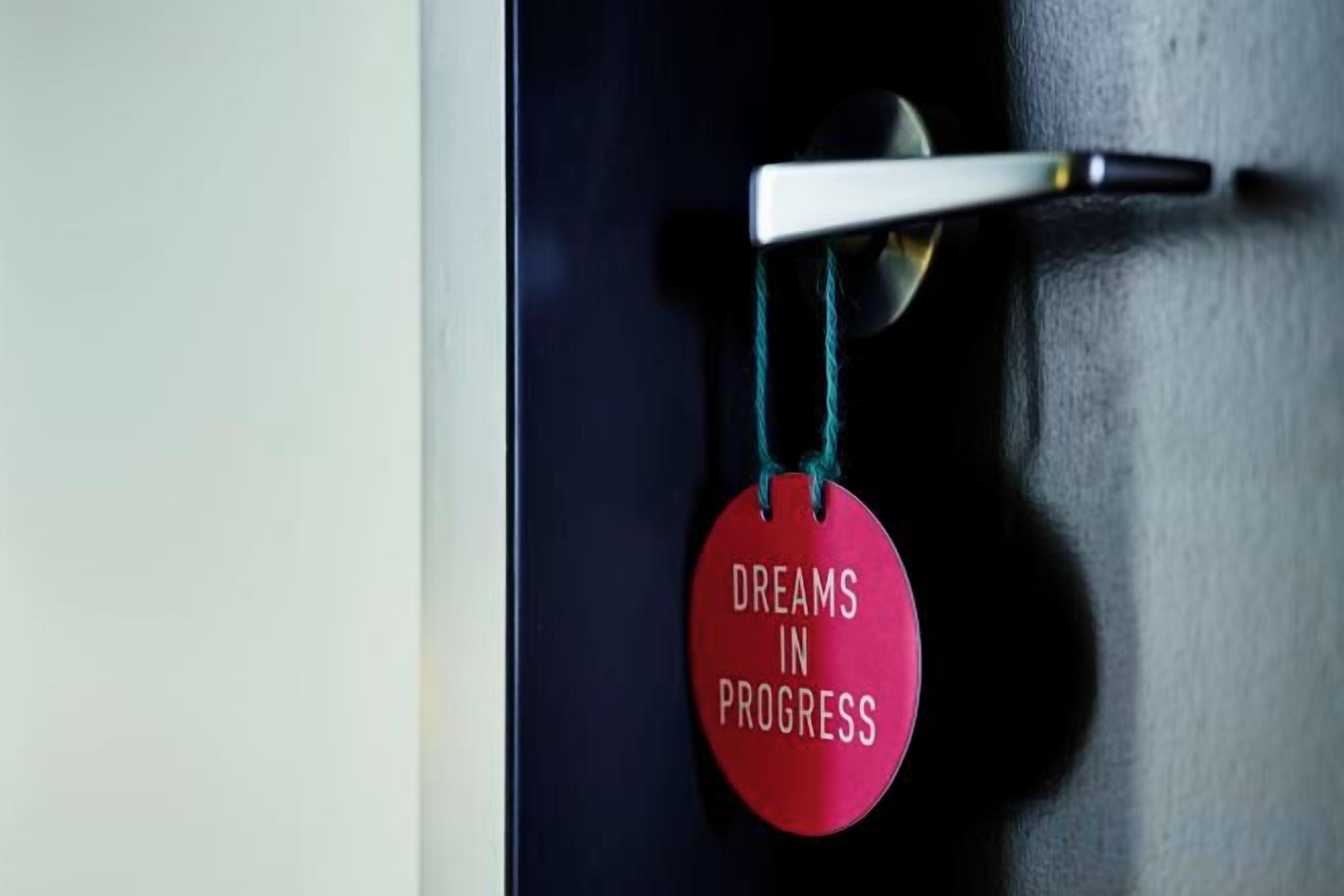 A door with a round, red tag hanging on a white handle.