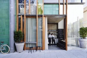 A modern building with a glass facade, wooden beams, and a seating area outside. - Alex Hotel (Northbridge)