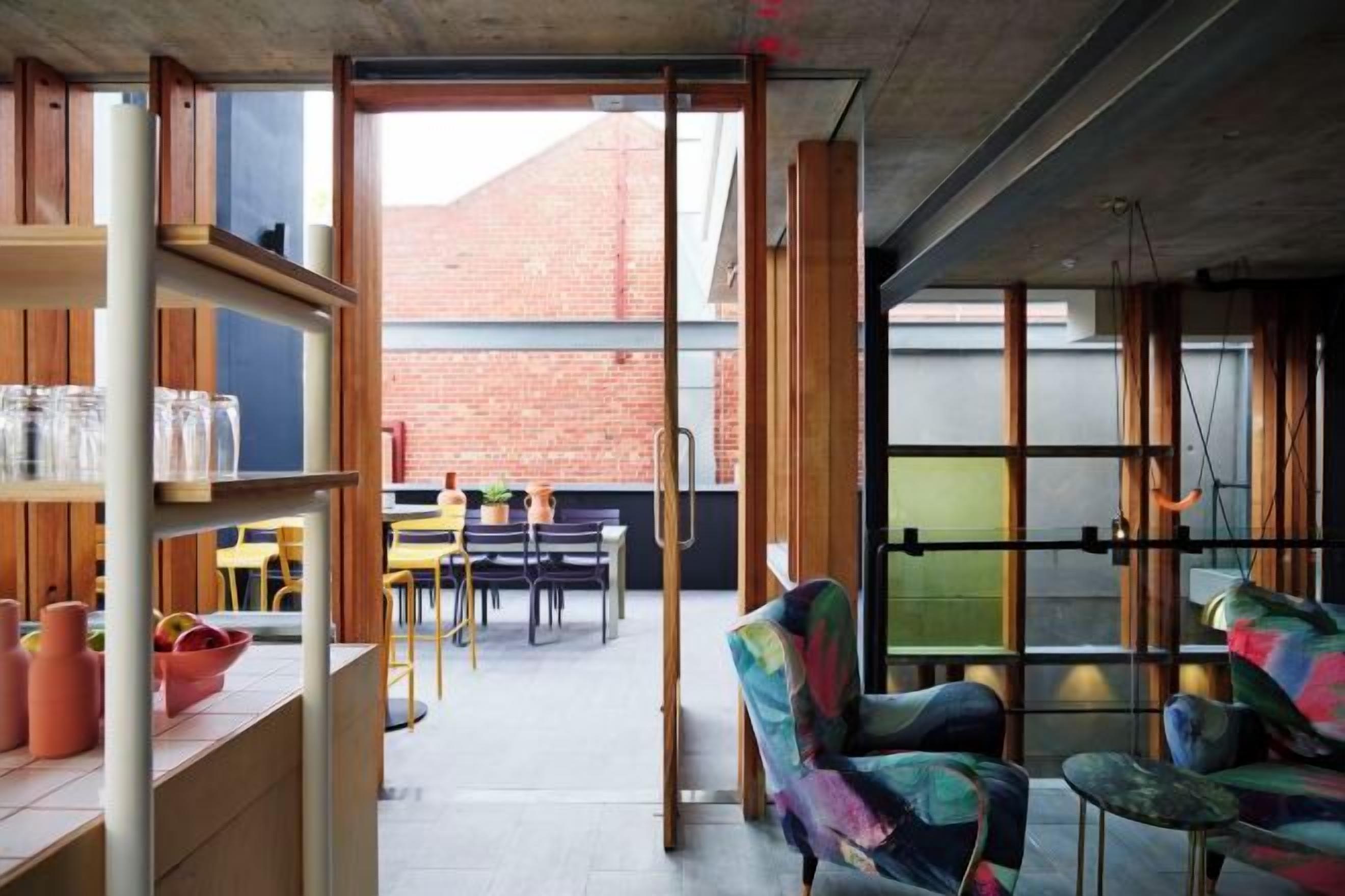 Un espacio interior con comedor, sillas y vistas a un edificio de ladrillo.