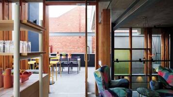 Un espacio interior con comedor, sillas y vistas a un edificio de ladrillo.