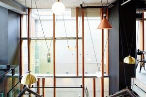 Um interior moderno com vigas aparentes, guarda-corpo de vidro e iluminação pendente.