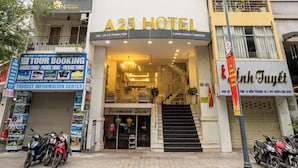 Un hôtel à la façade moderne, avec un panneau bien visible indiquant l’autoroute A25, et un escalier menant à l’entrée.