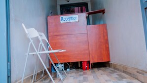 Et receptionsområde med et skilt, en klapstol og en rød spand.
